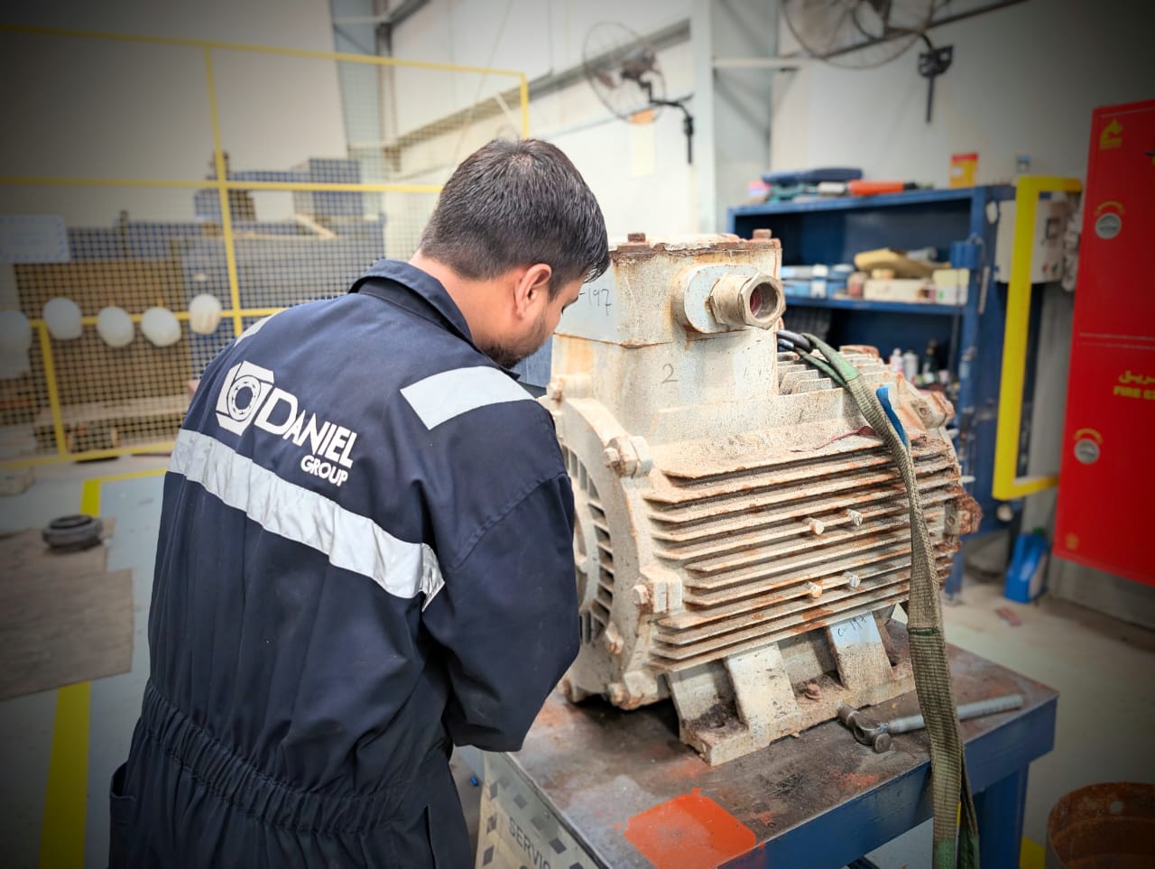 Technician performing Electric Motor Overhauling Procedure by rewinding the stator coils of a large industrial motor at Daniel Group workshop.