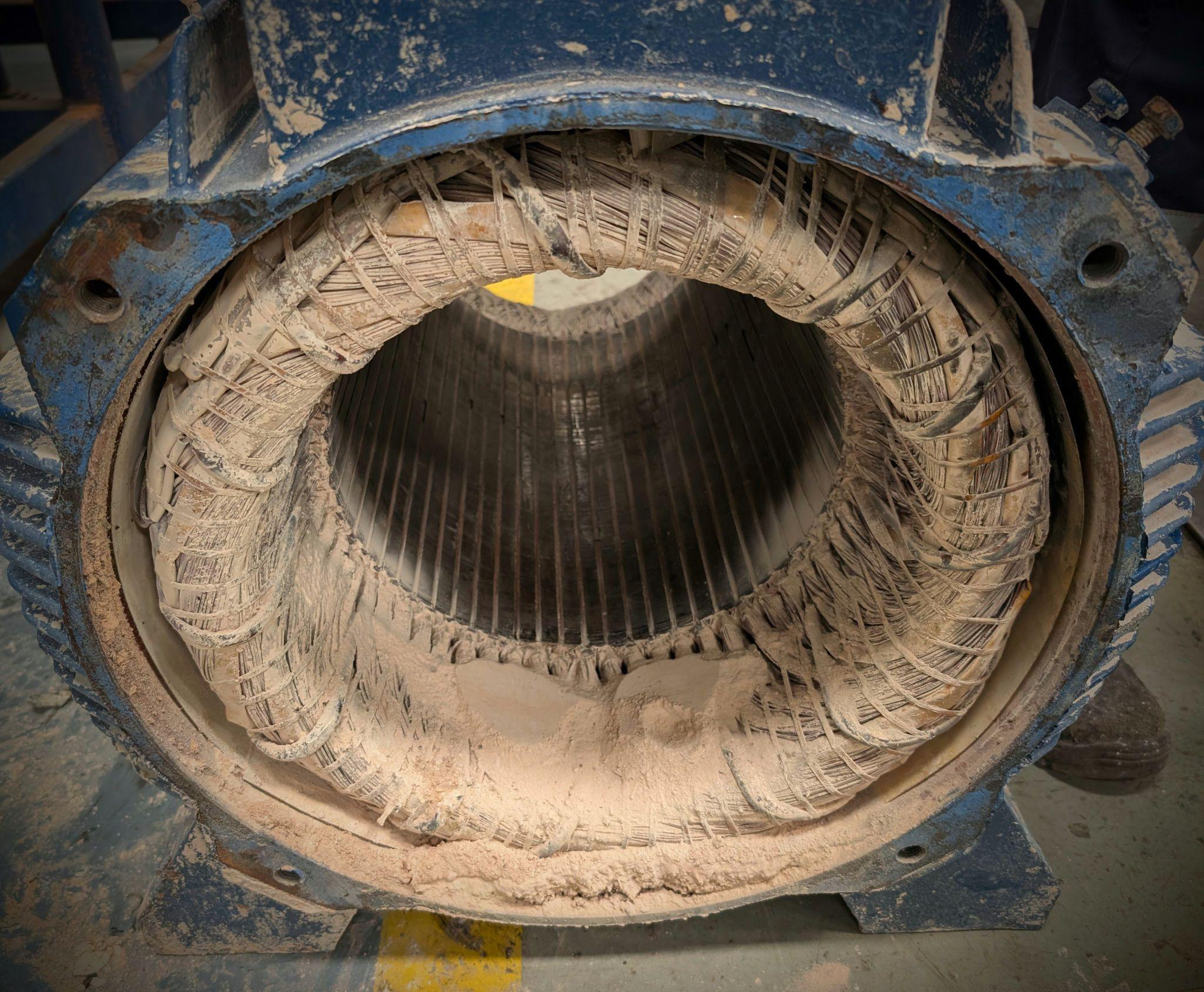 Motor stator interior packed with heavy cement dust contamination requiring specialised cleaning and overhaul