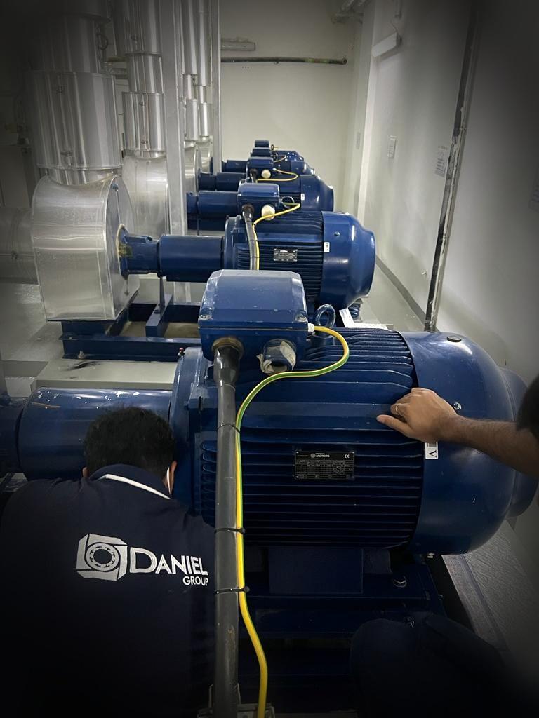 Daniel Group technicians inspecting chilled water pump motors in a building plant room